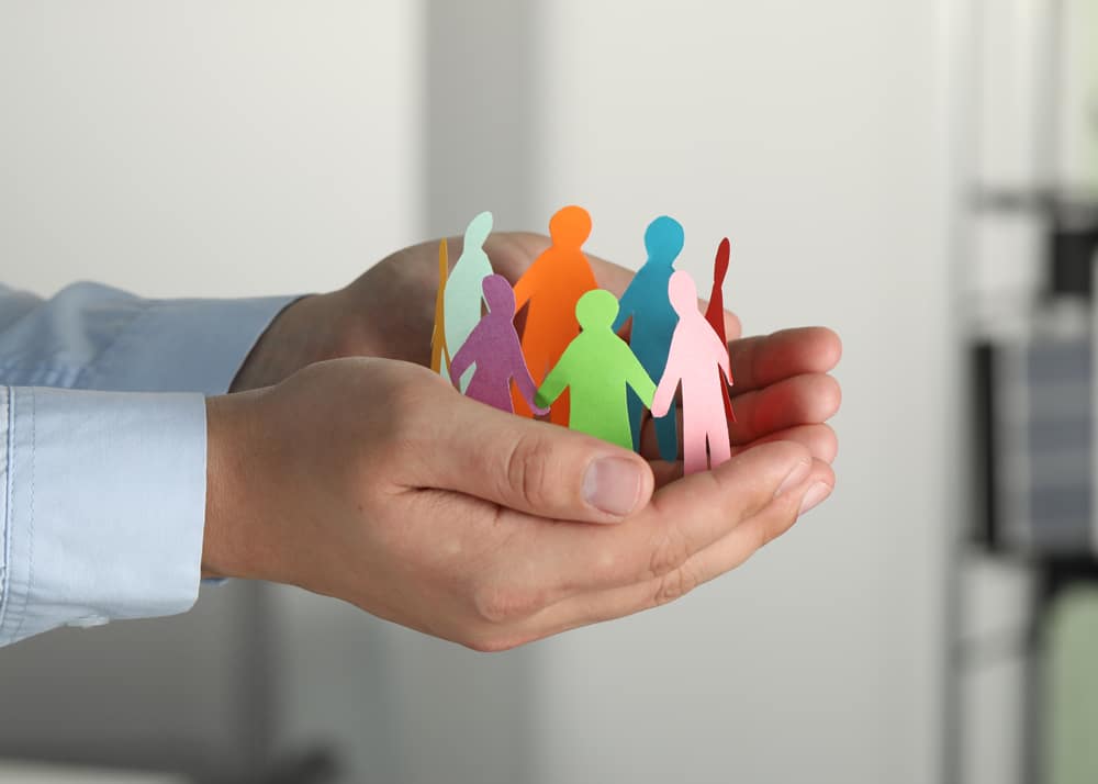 Hand hält Scherenschnitt einer Personengruppe