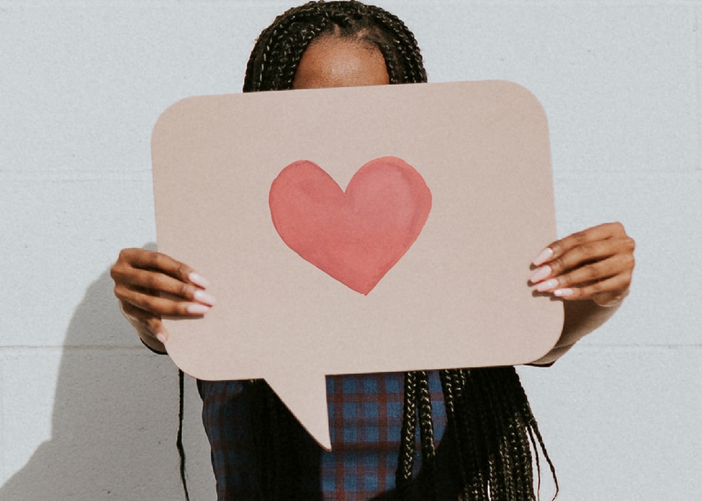 Frau hält Sprechblasen-Schild mit Herz drauf