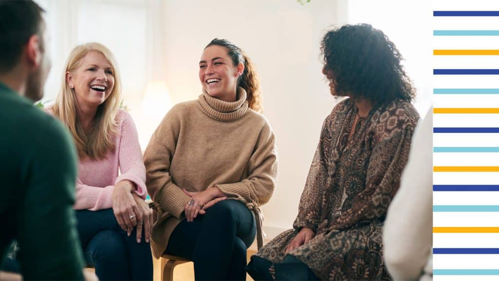 Selbshilfegruppe sitzt in lockerer Runde mit lachenden Menschen