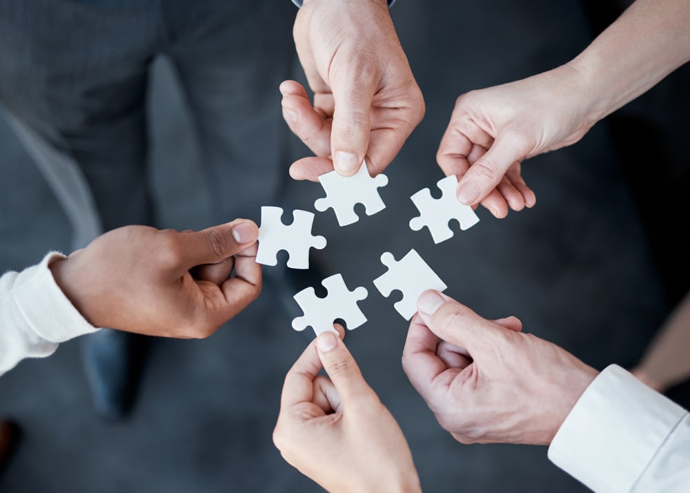 Hände halten Puzzle-Teile zusammen